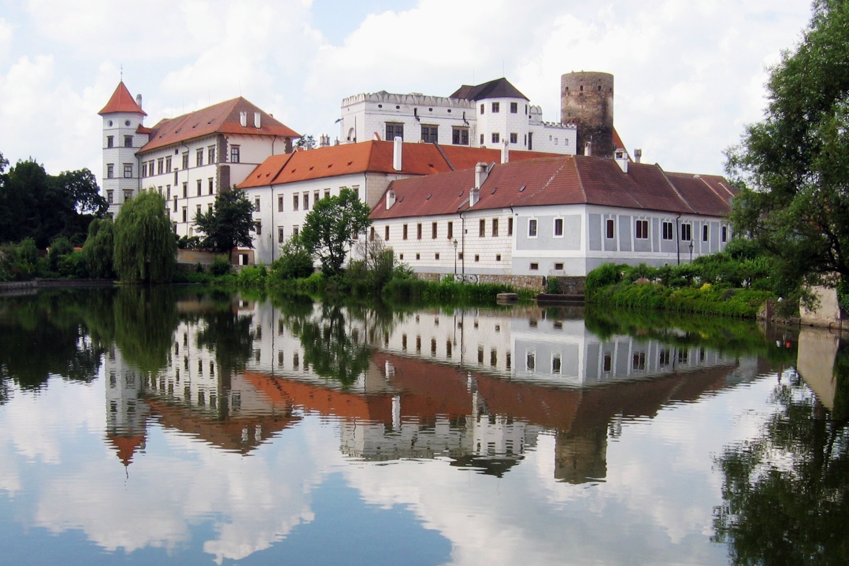 <h3>Zámek Jindřichův Hradec</h3><p>Město, které má své nepopiratelné kouzlo, láká zejména na svůj zámek. <strong>A Bílou paní! Ta se zjevuje hned na několika bývalých panstvích pánů z Rožmberku, ale Jindřichův Hradec prý navštěvuje nejčastěji</strong>. Prochází po chodbách a vstupuje do jednotlivých komnat. Není zlá, ale přece jen je potřeba být při setkání s ní ve střehu. Dokáže totiž předpovídat budoucnost. <strong>Co se bude dít, napovídá barva jejích rukaviček. Červené věští požár, černé úmrtí a bílé narození dítěte nebo svatbu</strong>. <em>(foto: Wikimedia Commons, Herbert Ortner, CC BY-SA 3.0)</em></p>