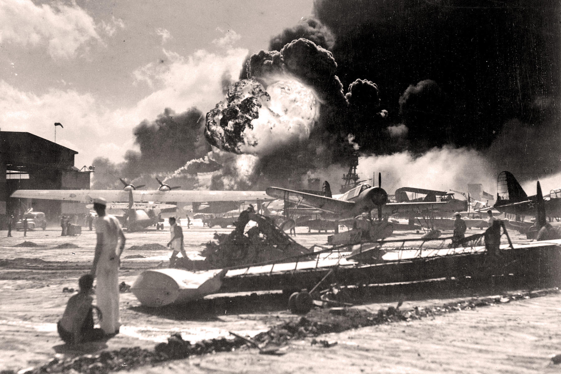<p>Námořníci na Fordově ostrově během japonského útoku na Pearl Harbor. V pozadí explodující torpédoborec <em>USS Shaw</em>.</p>