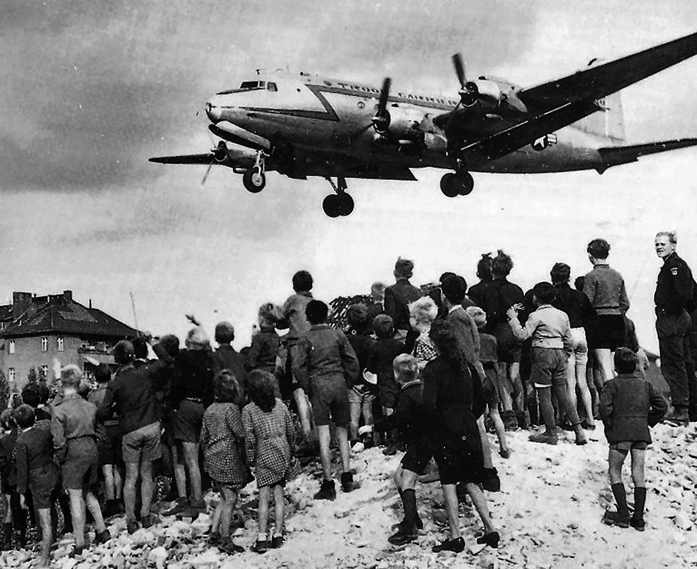 Blokáda Západního Berlína -<p>Američané začali po čase k  přepravě využívat obří dopravní letouny C-54. Denně se dopravilo až na 5 000 tun zboží. Na snímku Berlíňané pozorují přistávající C-54 na letišti Tempelhof (foto 1948)</p>